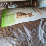 Eine große, durchsichtige Plastiktüte, gefüllt mit Katzentrockenfutter, mit einem Etikett mit dem Foto eines Kätzchens und Nährwertangaben, platziert zwischen anderen Tüten mit ähnlichem Tierfutter.