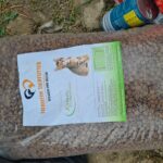 Eine große Plastiktüte Hundefutter mit der Aufschrift Tierheim Tierfutter und der Abbildung eines Hundes liegt im Freien auf dem Boden neben Dosen und etwas Gras.