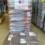 Ein Stapel verpackter Tierfuttersäcke liegt auf Paletten in einer Lagerhalle. Auf dem größeren Stapel ist ein Schild mit der Aufschrift "Tierheim Tierfutter Spenden und Helfen" angebracht, das auf Spenden und Hilfe für Tierheime hinweist.