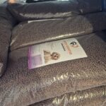 Klare Plastiktüten, gefüllt mit braunen Hundetrockenfutterpellets, sind übereinander gestapelt. Auf einem der Beutel ist ein Etikett mit der Abbildung eines kleinen Hundes und Fütterungsinformationen zu sehen.