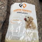 Eine Tüte Tierheim Tierfutter mit der Abbildung eines Golden Retrievers, der sich die Nase leckt. Auf dem Etikett steht "Premium Geflügel" und die Tüte wiegt 20 kg.