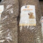 Zwei große durchsichtige Tüten, gefüllt mit Trockenfutter für Hunde. Die Etiketten auf den Beuteln zeigen das Bild eines Hundes und einen deutschen Text, darunter "Tierheim Tierfutter" und "Geflügel".