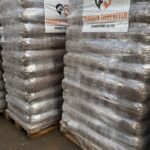 Mehrere große Stapel verpackter Tierfuttersäcke auf Holzpaletten mit der Aufschrift Tierheim Tierfutter und einem Herz- und Pfotenabdruck-Logo, die auf einer gepflasterten Außenfläche stehen.