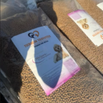 Große Tüten mit Hundetrockenfutter mit der Aufschrift "Tierheim Tierfutter" und der Abbildung eines Hundes sowie einem deutschen Text sind nebeneinander gestapelt; ein Schatten verdeckt teilweise eine der Tüten.