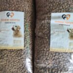 Zwei große Tüten Hundefutter mit der Aufschrift Tierheim Tierfutter und der Abbildung eines Hundes auf jedem Etikett. Die Tüten sind mit kleinen braunen Brocken gefüllt und der Text auf dem Etikett ist in deutscher Sprache.