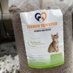 Eine große Tüte Katzenfutter mit der Aufschrift Tierheim Tierfutter und einem Foto eines Kätzchens, das auf verschneitem Boden sitzt. Auf dem Etikett steht, dass es sich um Premium-Trockenfutter für Katzen handelt, und es wird zu Spenden und Hilfe aufgerufen.