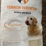 Eine Tüte deutsches Hundefutter mit der Aufschrift Tierheim Tierfutter, auf der ein Golden Retriever abgebildet ist, der sich die Nase leckt. Im Text werden auch Premium Geflügel und Trockenfutter für Hunde erwähnt.