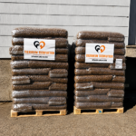 Zwei Holzpaletten, auf denen große, in Plastikfolie verpackte Säcke mit Tierfutter gestapelt sind. Auf jeder Palette befindet sich ein Schild mit der Aufschrift „Tierheim Tierfutter, Spenden und Helfen“ sowie einem Logo mit einem Herz und einem Pfotenabdruck; die Paletten stehen vor einem Gebäude.