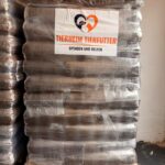 Eine Palette, auf der große, in Plastikfolie verpackte Säcke mit Tierfutter gestapelt sind. Auf einem Schild an der Vorderseite steht „Tierheim Tierfutter Spenden und Helfen“, daneben sind zwei Tiersilhouetten und ein Herz-Logo abgebildet.