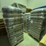 Drei Paletten mit in Schrumpffolie verpackten Säcken, die in einem Lager gestapelt sind.