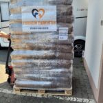 Eine Palette mit in Plastikfolie verpackten Säcken mit Tierfutter, an der ein Schild mit der Aufschrift Spende für Tierheim Tierfutter angebracht ist.