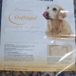 Ein Sack Hundefutter mit der Aufschrift „Tierheim Tierfutter“ und dem Bild eines Golden Retrievers. Der Text enthält die Angaben „Premium Geflügel“ sowie Informationen zu Spenden. Durch die Verpackung sind braune Trockenfutterbrocken zu sehen.
